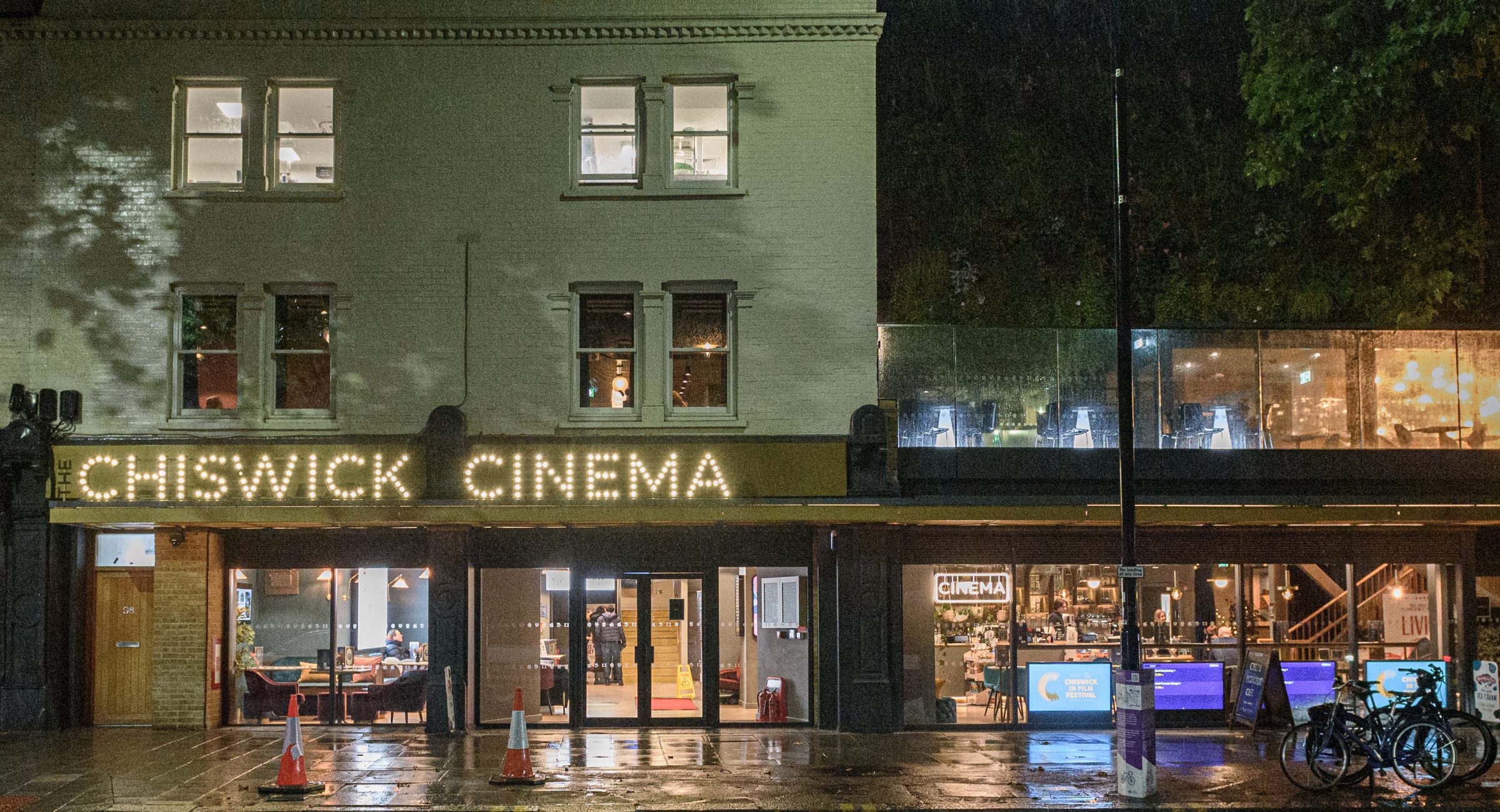 Exterior soft focused shot from the other side of the street of the venue in the rain.